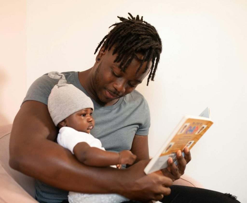 A Man Reading a Book to his Baby